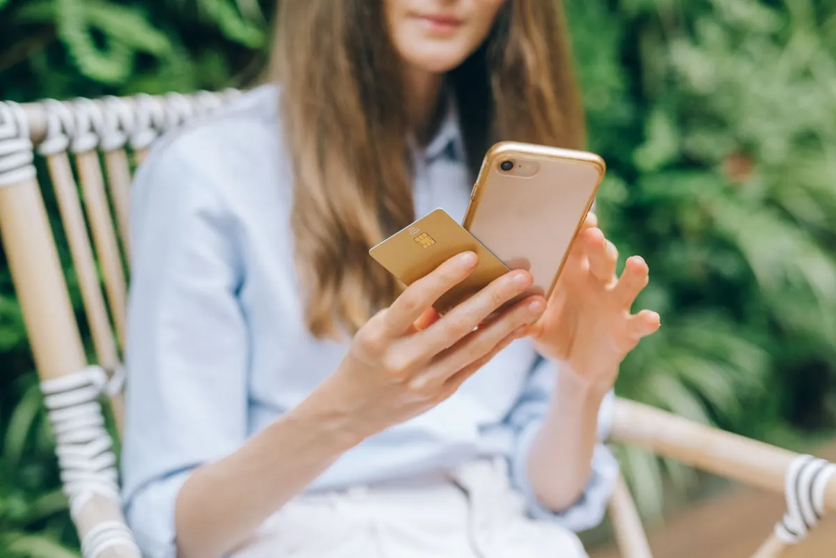 A person paying online with her phone and a card